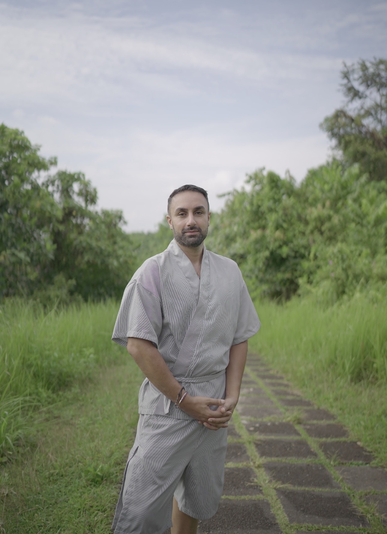 Mani standing on a stone path through lush greenery, guide and facilitator of the Inner Union pathways