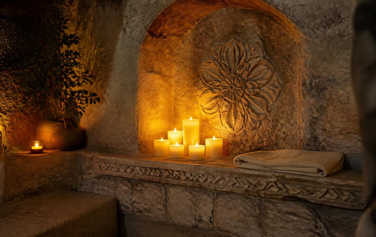 Candlelight glowing against a carved natural stone alcove in a quiet sacred space